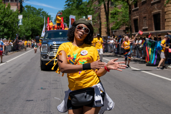 An employee walking in front of the McDonald’s float, grinning and dancing in the street as the Pride Parade progresses through the city of Chicago